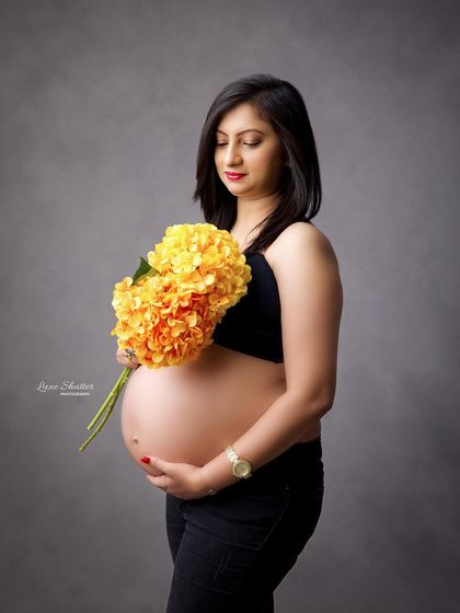 A pop of color can brighten up a minimalist shoot. The bright yellow flowers provide a beautiful contrast to the simple black outfit and grey backdrop.