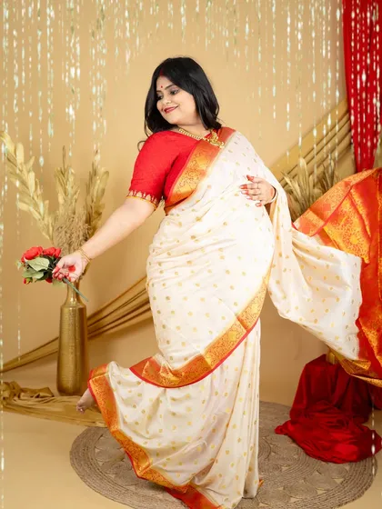 A graceful and dynamic shot of a mom-to-be in a traditional white and red saree. Her pose and the flowing fabric create a sense of movement and celebration.
