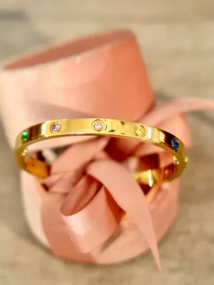 This elegant gold-tone bangle, dotted with multi-colored crystals, is a beautiful and timeless Valentine's gift. It comes perfectly presented in our signature gift box with a pink ribbon.