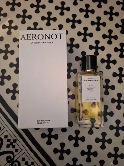 A flat lay featuring a blazer from Attic Salt and a bottle of Tuscany Brunch perfume from Aeronot.