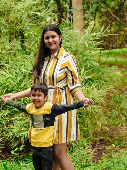 A mother and son enjoying a playful moment in the park. The lush green background provides a beautiful setting for this happy outdoor portrait.