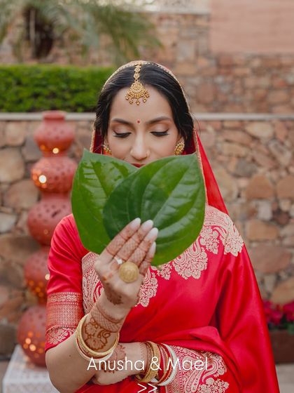 A traditional Bengali wedding moment. The makeup is designed to look beautiful from every angle, even behind the ceremonial paan leaves.