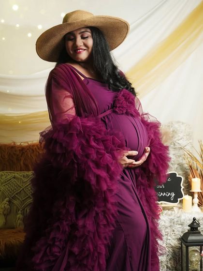A gentle, loving pose in our boho-themed setup. The mom-to-be cradles her bump, surrounded by soft textures and warm candlelight, creating a cozy and artistic portrait.