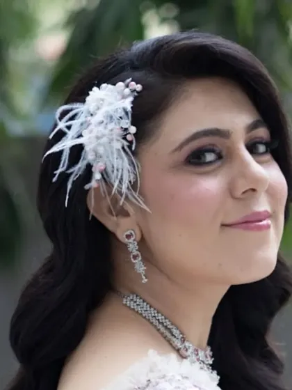 A close-up of the wavy hairstyle and feather accessory. I pay close attention to detail to ensure every element of the look is perfectly placed and secure.