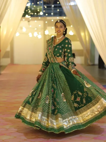 A stunning Gujarati Sangeet look. The client is twirling in a beautiful green lehenga, her makeup glamorous and ready for a night of dancing.