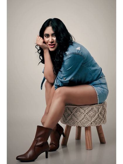 A relaxed and confident studio portrait. The denim-on-denim look and the model's easy smile create a friendly and approachable vibe.
