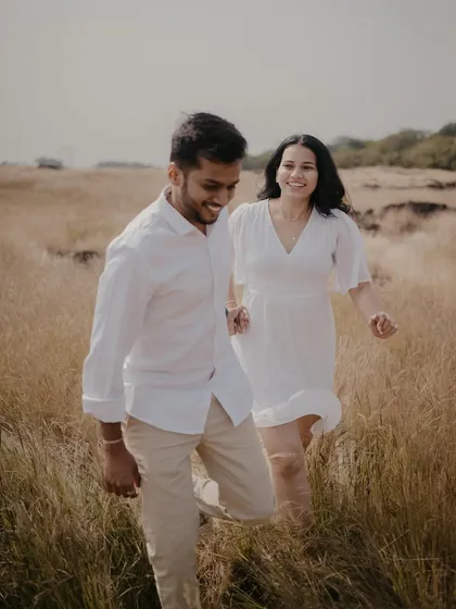 Capturing a fun, candid moment as the couple runs through a field of tall grass near Pune. Their coordinated white outfits and genuine smiles make this a lighthearted and joyful pre-wedding photo.