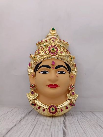 A hand-painted clay Lakshmi face with a serene expression, adorned with a golden crown and jewellery. Perfect for a traditional Varamahalakshmi setup.