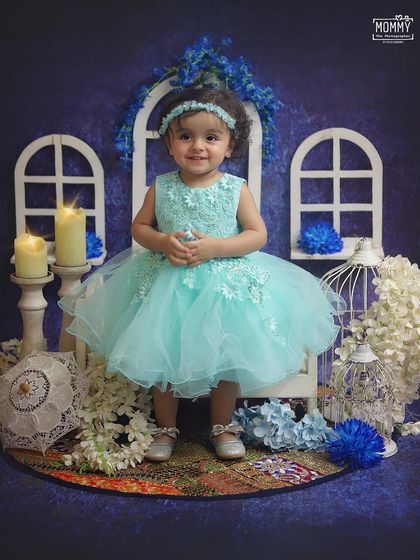 A vision in blue! This sweet little girl is all smiles in our dreamy blue-themed studio setup, complete with white window props, candles, and flowers.