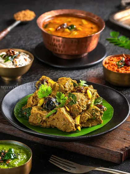 A flavorful South Indian chicken dish served on a banana leaf, surrounded by traditional sides.