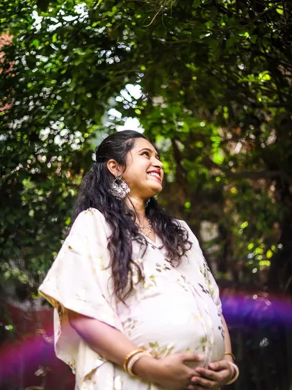 This is a portrait of pure joy. We used the natural garden light and a subtle lens flare to create an artistic, dreamy photo that captures the mother-to-be's happiness and excitement. This style of solo maternity portrait focuses on authentic emotion.
