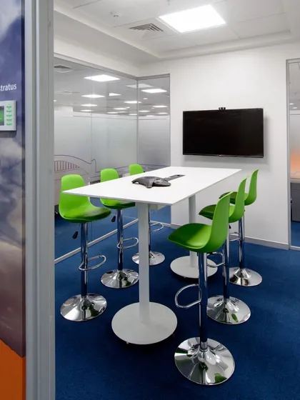 A meeting room with bright green bar stools and a high table. The design is fresh, modern, and perfect for a dynamic tech company.