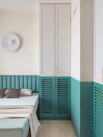 For the parents' room, we used a two-tone color scheme with white and teal. The lower half of the walls and the louvered wardrobe doors are painted in a calming teal, which adds a subtle pop of color while maintaining a serene atmosphere.