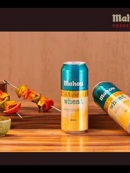 A crisp Mahou Wheat beer paired with vibrant paneer tikka skewers. This shot is designed to create a craving by showcasing the perfect food and drink combination for a social setting.