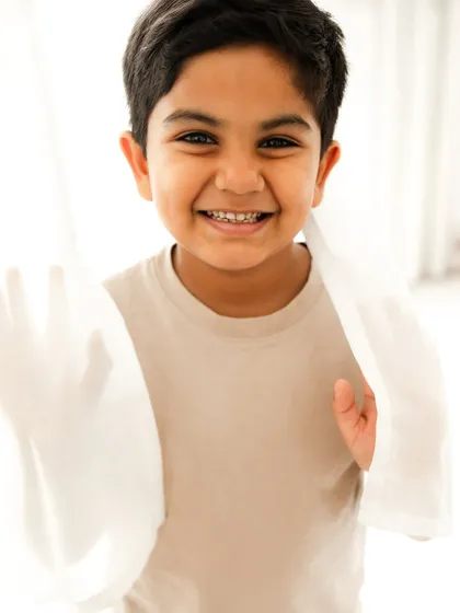 A bright and happy portrait of a young boy. The simple, light-filled setting allows his wonderful smile to be the star of the show.