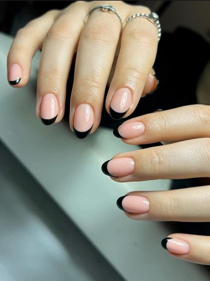 A bold and classic black French manicure on short, rounded nails for a striking yet simple statement.