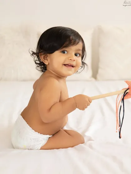 Playtime is the best time for photos. This little one's happy expression while playing on the bed is a perfect candid moment.