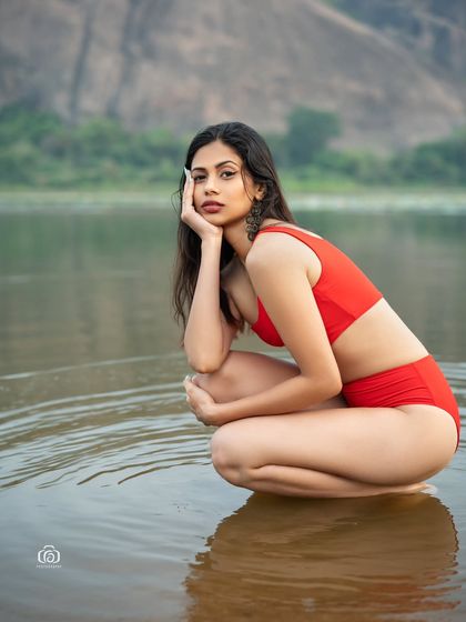 A kneeling pose in the water, with the model looking thoughtfully into the distance. The calm water and the soft light create a peaceful and serene mood.