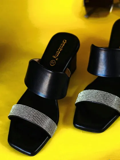 A top-down view of the black and silver heels, clearly showing the design and branding on the insole for a complete product view.