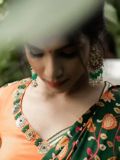 A close-up of the metallic orange and bottle green half saree. The blouse neckline is adorned with intricate, handcrafted bead and thread work in a temple design.