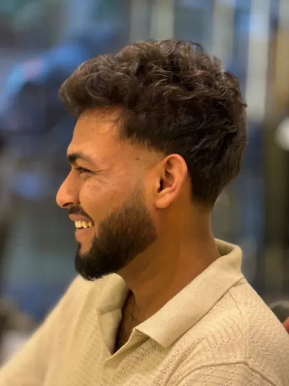 A smiling client, happy with his new haircut. The fade is perfect and the curly top is styled for a modern look.
