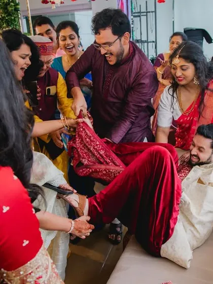 The whole family gets involved in the shoe-stealing game. This image is filled with movement, laughter, and the joyful chaos that makes Indian weddings so special.