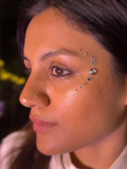 A simple yet stunning crescent of clear rhinestones accenting the eye. This is a perfect example of how face gems can elevate your look in a very chic and minimalist way.