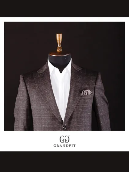 A close-up of the brown plaid jacket, styled simply with a white shirt to let the rich pattern and expert tailoring take center stage.