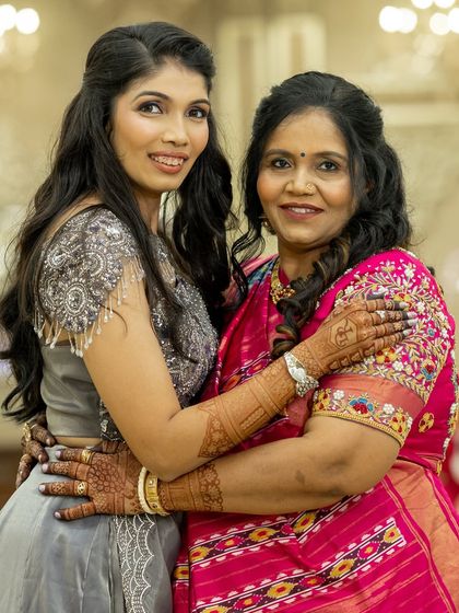 A heartwarming hug between a mother and daughter, both showcasing their elegant party mehendi.