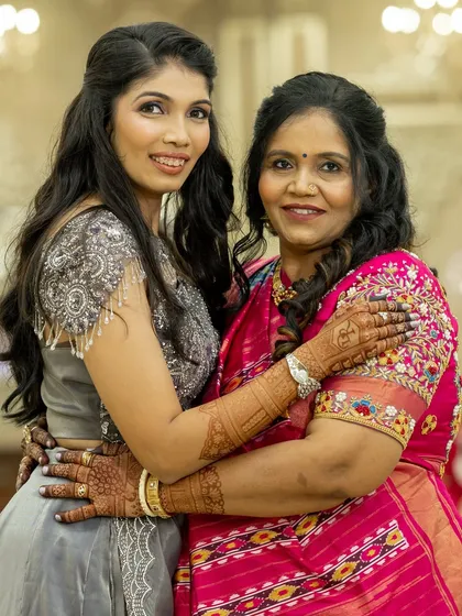 A heartwarming hug between a mother and daughter, both showcasing their elegant party mehendi.