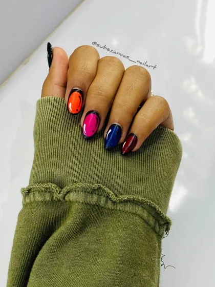 A fun and unique comic book or pop art nail design. Each nail is painted with a vibrant color and outlined in black to create a 2D cartoon effect.