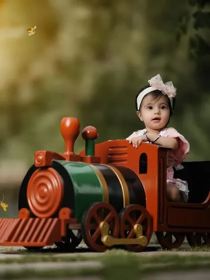 A beautiful, sunny day for a train ride. This little girl's smile lights up the photo as she enjoys her time on the colorful toy train.