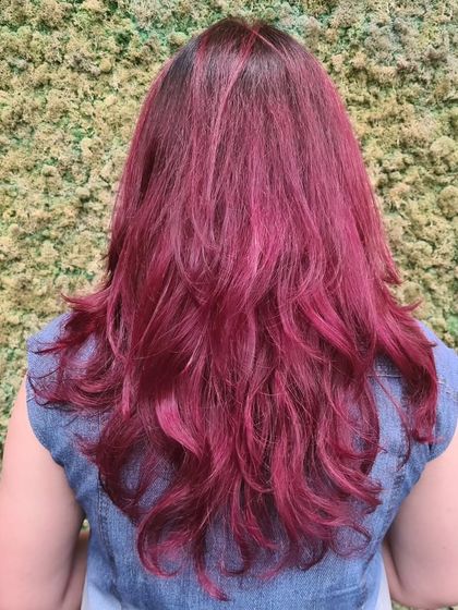 A vibrant, all-over magenta hair color with layers to add movement and show off the bold shade.