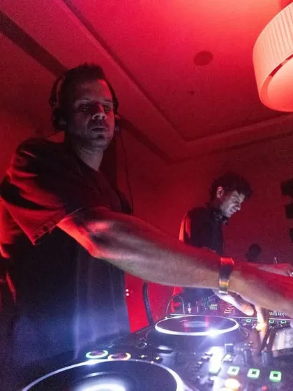 A DJ in his element, surrounded by the warm red glow of the stage lights. We ensure every artist has the perfect environment to deliver their best performance.