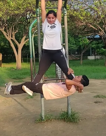 This is a challenging partner exercise using the pull-up bars. While I work on my grip strength by hanging, my partner performs crunches, using my legs for support.