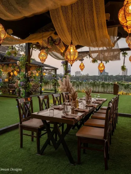 I designed this intimate alfresco dinner setting for a rustic yet romantic feel. The long wooden table, warm Moroccan-style lanterns, and soft fabric draping create a cozy and inviting atmosphere for a special milestone celebration.