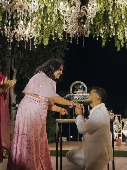 A romantic proposal during the cocktail party, set under a canopy of hanging greenery and magnificent chandeliers.