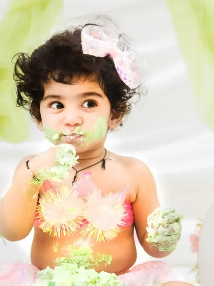 A cheeky, sideways glance while enjoying her cake. I aim to capture the full range of your baby's personality during their session.