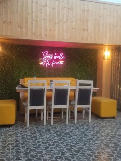 A cozy seating nook at the restaurant, featuring a neon sign on a green wall and comfortable yellow seating, creating a perfect photo opportunity for guests.