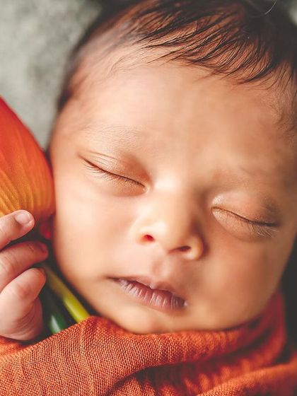 A newborn's tiny hand grasping a vibrant tulip. This macro shot emphasizes the delicate and precious details of your new baby.
