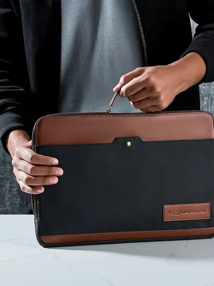 A lifestyle shot for The Postbox, showing their laptop sleeve in use. The human element makes the product relatable, and the textured background adds a touch of modern, industrial style.