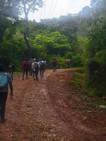 A group of adventurers on a muddy trail during a monsoon trek. We embrace the rain and the lush greenery it brings.
