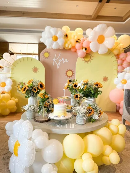 A sunny and cheerful first birthday party. The theme was brought to life with daisy and sun-shaped balloon arches, fresh sunflowers, and a custom backdrop, creating a joyful space for a little one's big day.
