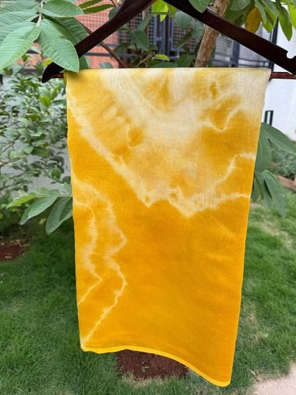 This saree features a more abstract, cloud-like pattern, also created with marigold dye. Each hand-dyed saree is a unique piece of wearable art.