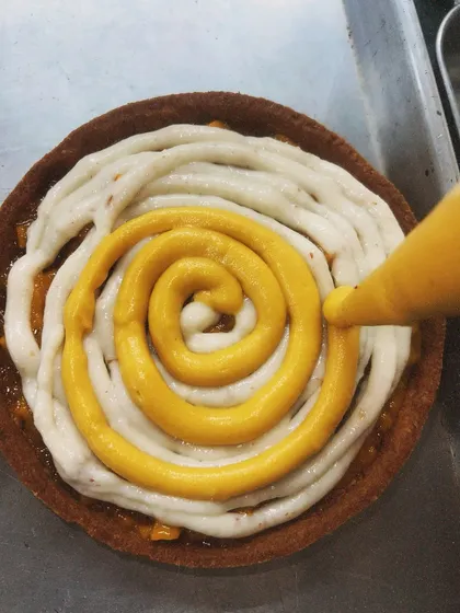 Piping a swirl of mango cream on top of the vanilla cream. The layers of flavor are what make this tart so special.