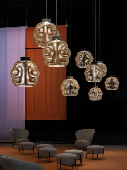 A large cluster of Seppo Koho's cloud-inspired pendants creates a captivating statement in this lounge area. The arrangement feels like a floating sculpture, filling the vertical space with warmth and texture.