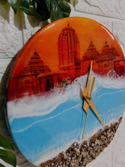 This side view highlights the glossy finish and vibrant colors of the Jagannath Puri clock, from the warm orange sunset sky to the cool blue of the ocean.