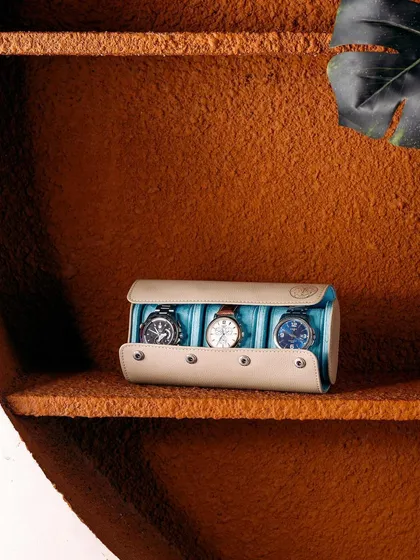 A Verman Atelier leather watch roll, elegantly styled on a textured shelf. This shot showcases the product as a sophisticated solution for storing and protecting valuable timepieces.