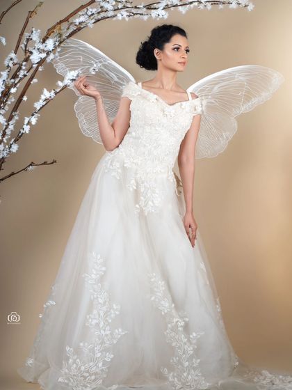 A whimsical and magical portrait, with the model in a white gown and fairy wings, standing by a white branch. This is a perfect example of a creative, fantasy-themed photoshoot.