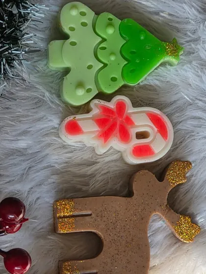 A trio of Christmas-themed soaps: a Christmas tree, a candy cane, and a reindeer.